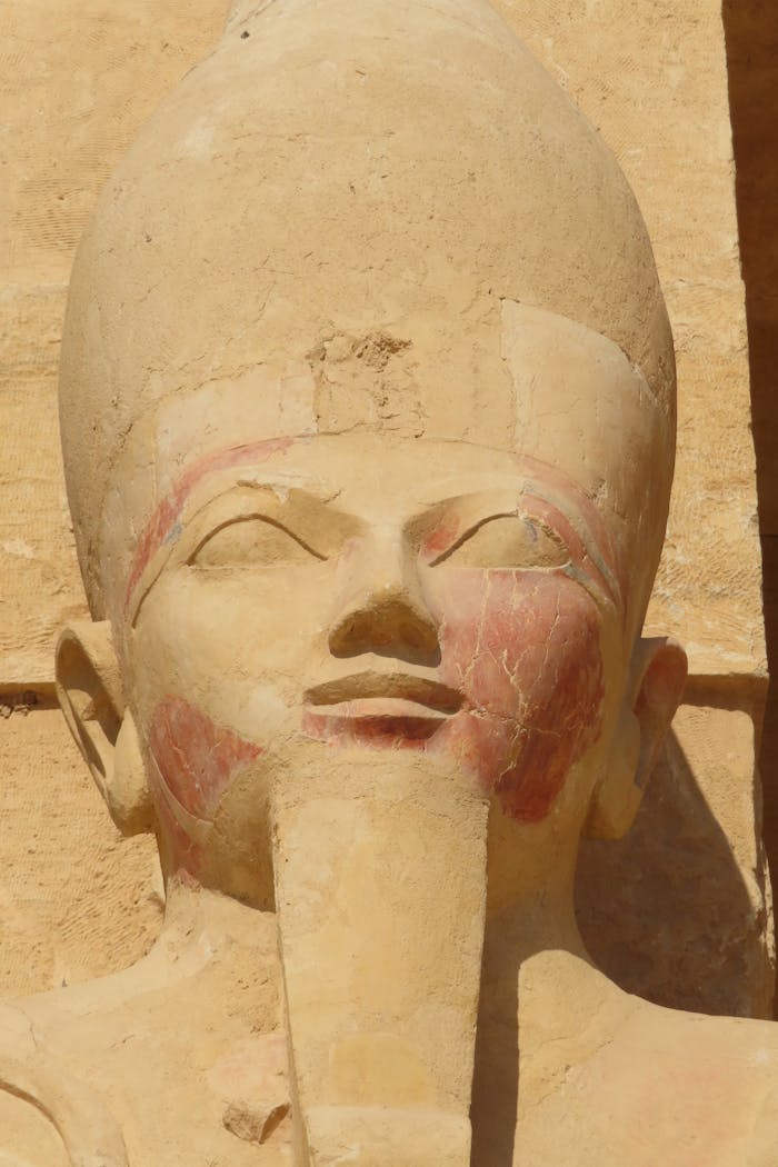 Accueil Close-up of an ancient Egyptian stone sculpture depicting a pharaoh's head.